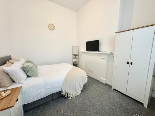 a white bedroom with a bed and a cabinet at City Haven - 2 Bed in Sheffield - LuxeSuites in Midland
