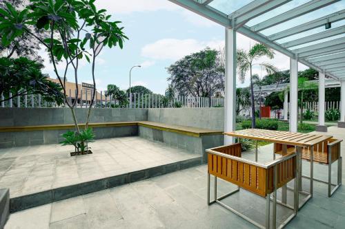 a patio with a table and benches and trees at Holiday Inn Express Jakarta International Expo by IHG in Jakarta