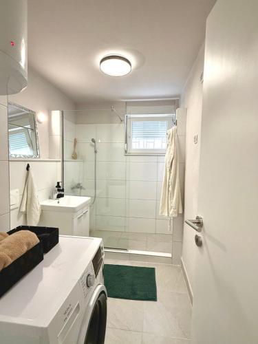 a bathroom with a shower and a washing machine at Studio Apartment 1906 in Mostar