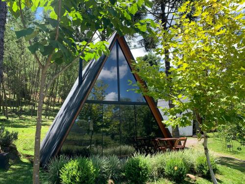 a triangular house in a garden with a large window at Cabana Amélia, em Gramado in Gramado