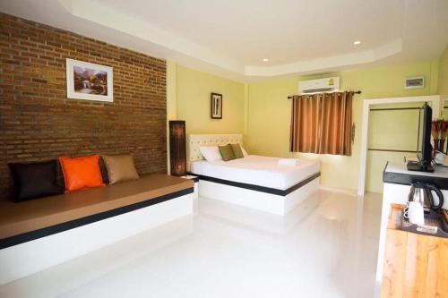 a bedroom with two beds and a brick wall at บ้านไร่แสงเดือน รีสอร์ท in Ban Kha