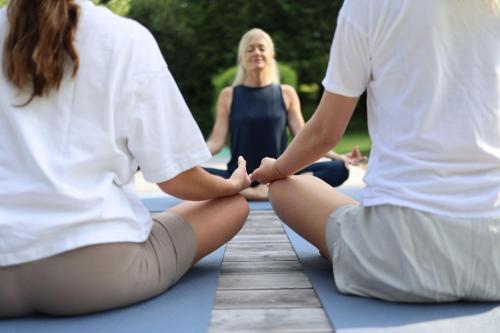 a group of people sitting in aorative yoga pose at Ritzenhof - Hotel und Spa am See 4-Sterne-Superior in Saalfelden am Steinernen Meer