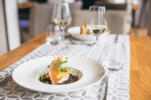 a plate of food on a table with wine glasses at Ritzenhof - Hotel und Spa am See 4-Sterne-Superior in Saalfelden am Steinernen Meer