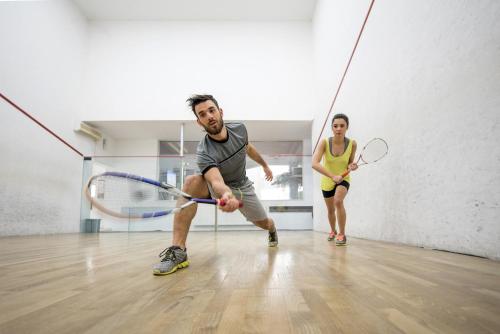 a man and a woman playing a game of tennis at Amenity Hotel & Resort Lipno in Lipno nad Vltavou