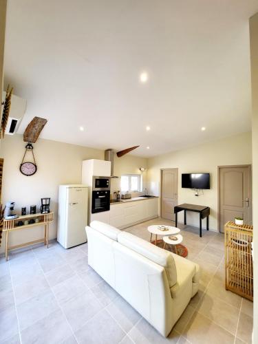 a living room with a white couch and a kitchen at Maison au calme - Clim - Wi-Fi - terrasse et cours in Salles-d'Aude