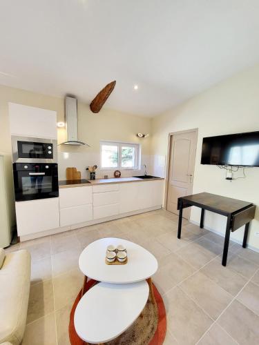 a living room with a table and a kitchen at Maison au calme - Clim - Wi-Fi - terrasse et cours in Salles-d'Aude