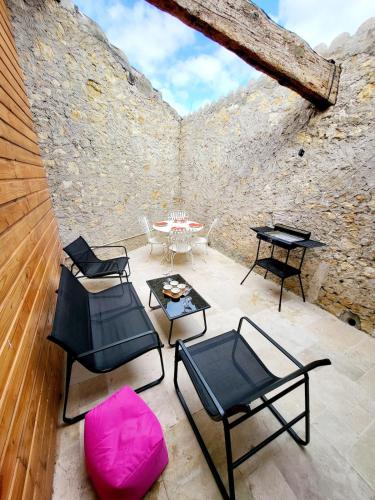 a patio with chairs and a table in a stone wall at Maison au calme - Clim - Wi-Fi - terrasse et cours in Salles-d'Aude