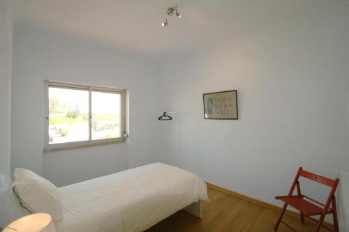 a white bedroom with a bed and a chair at Queluz Apartment in Queluz