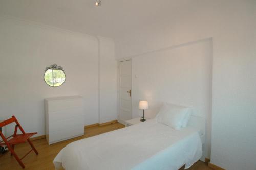 a white bedroom with a bed and a chair at Queluz Apartment in Queluz