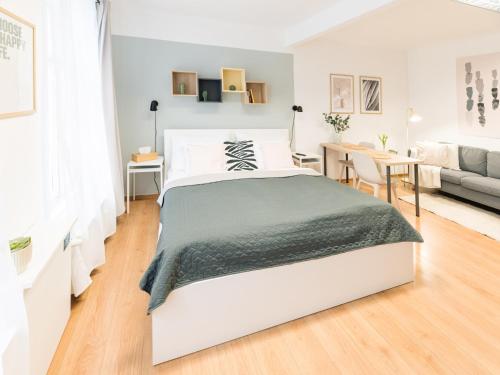 a white bedroom with a bed and a living room at 7nights Apartments Dominikánské naměstí in Brno