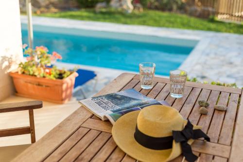 a hat and a magazine sitting on a wooden table at Crete Essence Villas - Lagkada in Makry Gialos