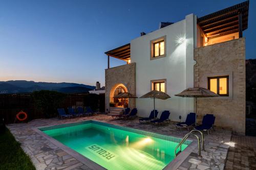 a villa with a swimming pool in front of a house at Crete Essence Villas - Lagkada in Makry Gialos