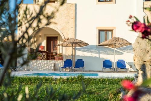 a house with chairs and umbrellas next to a pool at Crete Essence Villas - Lagkada in Makry Gialos