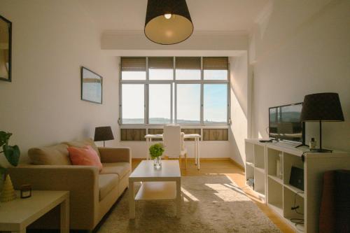 a living room with a couch and a tv at Queluz Apartment in Queluz