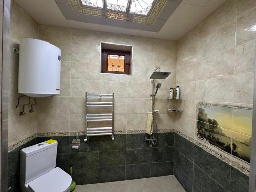 a bathroom with a toilet and a window at Gabala Riverside House in Gabala