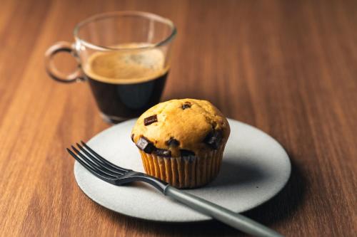 a muffin on a plate with a fork and a cup of coffee at The Royal Park Canvas - Kobe Sannomiya in Kobe