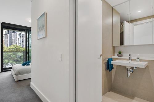 a white bathroom with a sink and a bed at 47OP Elegant Parkview Abnb-Style 2BR Retreat with Free Parking in Sydney
