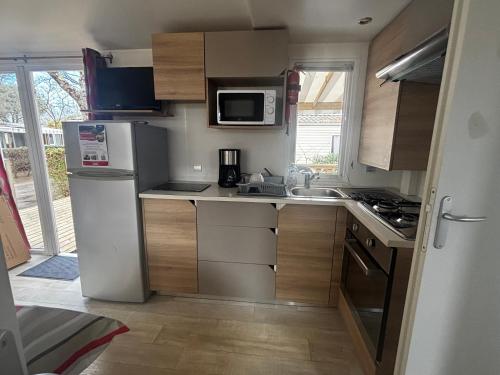 une petite cuisine avec un réfrigérateur et un micro-ondes dans l'établissement Mobil home 8 places, à Gastes