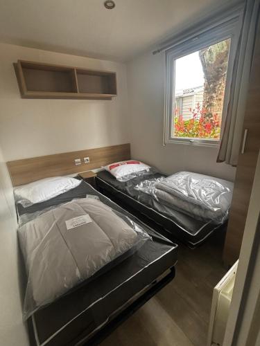 deux lits dans une petite pièce avec une fenêtre dans l'établissement Mobil home 8 places, à Gastes