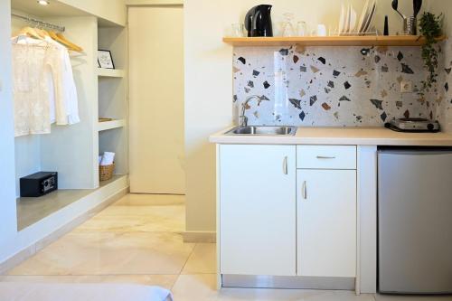 a kitchen with white cabinets and a tile floor at Cozy Studio #10 in Malia