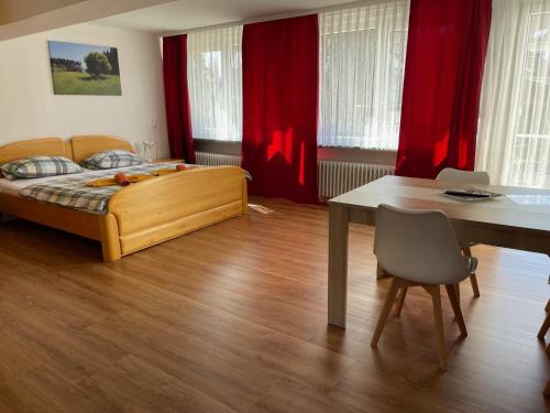 a bedroom with a bed and a table and red curtains at Naturkost-Hotel Harz in Bad Grund