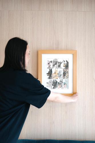 a woman is holding a picture on a wall at Boutique Macchiato Rooms in Novi Sad