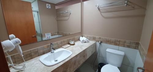 a bathroom with a sink and a toilet and a mirror at Le Jardin Suites Luxo - Central de Reservas in Caldas Novas