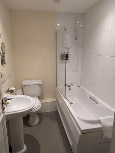 a bathroom with a toilet and a tub and a sink at Gordon Arms Hotel in West Linton