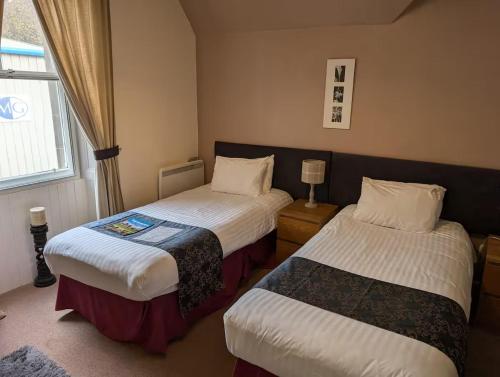 a hotel room with two beds and a window at Gordon Arms Hotel in West Linton