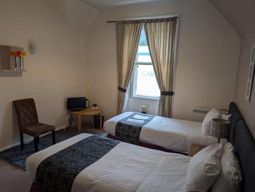a hotel room with two beds and a window at Gordon Arms Hotel in West Linton