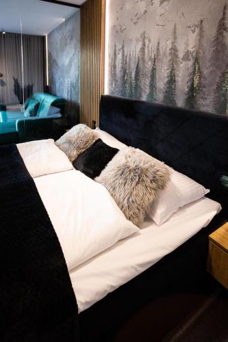 a large bed with white sheets and fur pillows at Apartament z prywatnym jacuzzi z widokiem na góry 109 KRAS RESORT in Szklarska Poręba