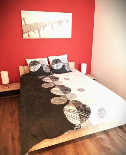 Ce lit se trouve dans une chambre dotée d'un mur rouge. dans l'établissement L'écureuil, à Châteauneuf-sur-Loire