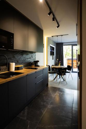 a kitchen with black cabinets and a dining room at Apartament z prywatnym jacuzzi z widokiem na góry 109 KRAS RESORT in Szklarska Poręba