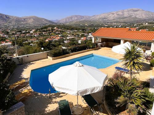a swimming pool with an umbrella and a house at Bella Vista pool Villas in Anavissos in Barbaliáki