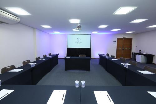 a conference room with tables and chairs and a screen at Itu Plaza Hotel in Itu