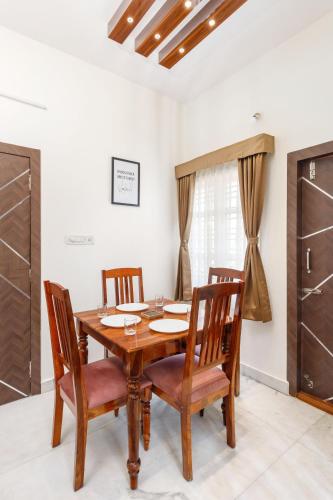 a dining room with a wooden table and chairs at Mistyblue Suites in Bengaluru