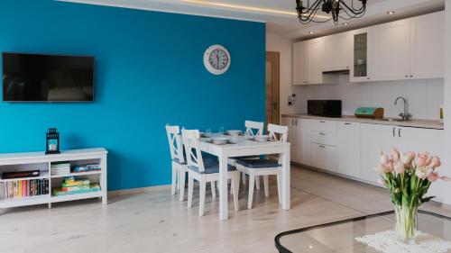 a kitchen with a table and chairs and a blue wall at Baltic Korona, Sun & Snow in Darłowo