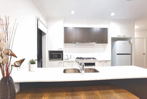 a white kitchen with a sink and a refrigerator at New, Spacious and Cozy Home at Austral in Austral