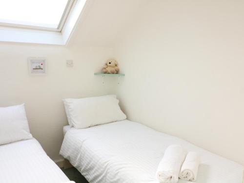 two beds in a room with a teddy bear on a shelf at Millers Loft in Ivybridge