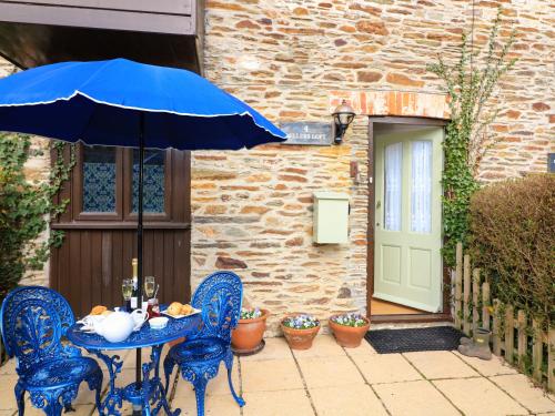 a table and chairs with an umbrella in front of a building at Millers Loft in Ivybridge