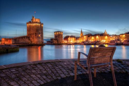 a chair sitting next to a river with a castle at Charming 100m2 House in Croix-Chapeau, 15mn from La Rochelle in Croix-Chapeau
