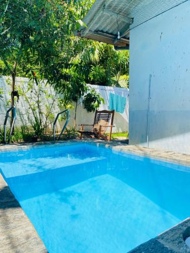 a blue swimming pool with a chair and an umbrella at New King well resort and guest house in Ahangama