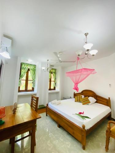 a bedroom with a bed with a pink umbrella on it at New King well resort and guest house in Ahangama
