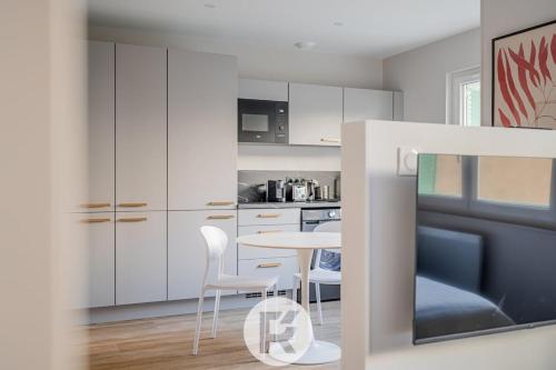 une cuisine avec des armoires blanches et une table et des chaises dans l'établissement R'Appart L'atelier Voyageur S1, à Grenoble