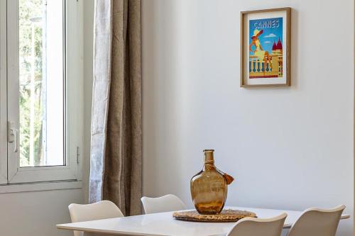 une salle à manger avec une table avec un vase dessus dans l'établissement LE COSY un havre de paix près de la Croisette, à Cannes