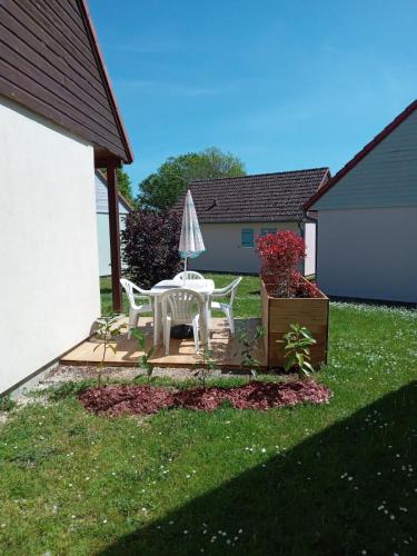 un patio avec une table et un parasol dans une cour dans l'établissement Marina près du Lac, à Giffaumont
