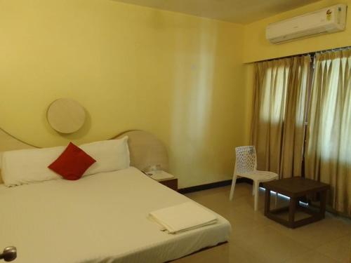 a bedroom with a bed with a red pillow and a chair at SHIVANGAN HOTEL and BANQUET in kolkata