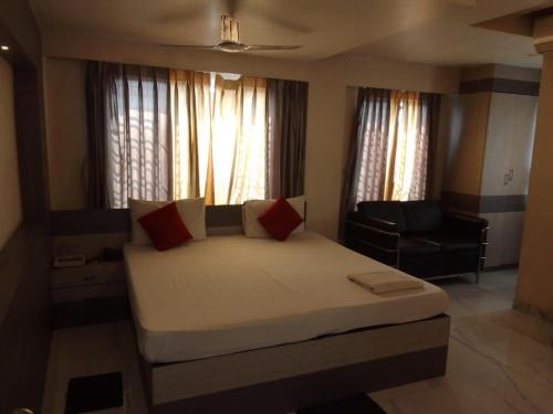 a bedroom with a bed and a chair and windows at SHIVANGAN HOTEL and BANQUET in kolkata