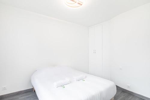- un lit blanc dans une chambre aux murs blancs dans l'établissement GuestReady - Peaceful Retreat in Canal St Martin, à Paris