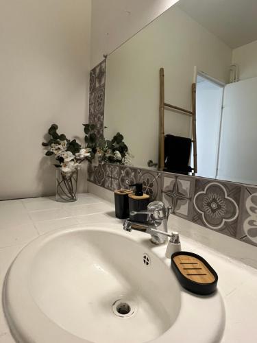 Appart au pied du T2 La Défense Paris في بيزونس: حمام مع حوض أبيض ومرآة